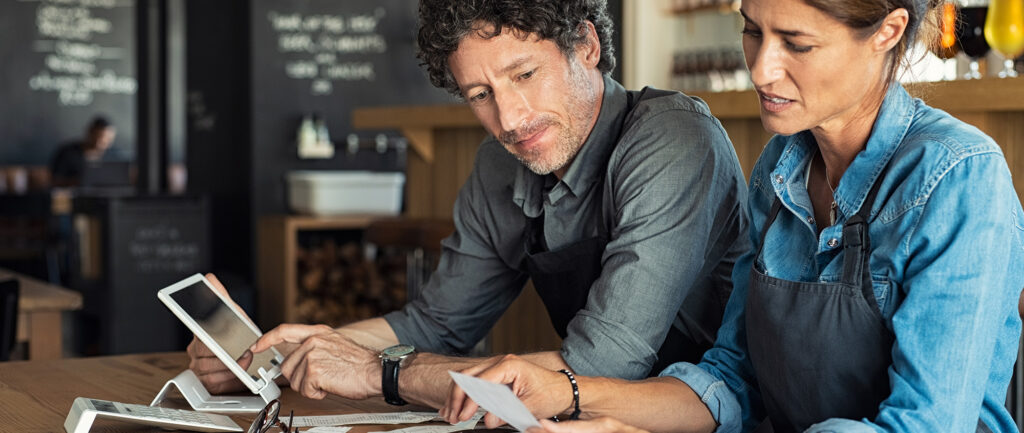 Two concerned restaurant owners review receipts and put into accounting software