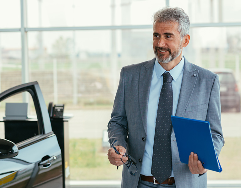 A sales professional walking around a showroom in a car dealership.